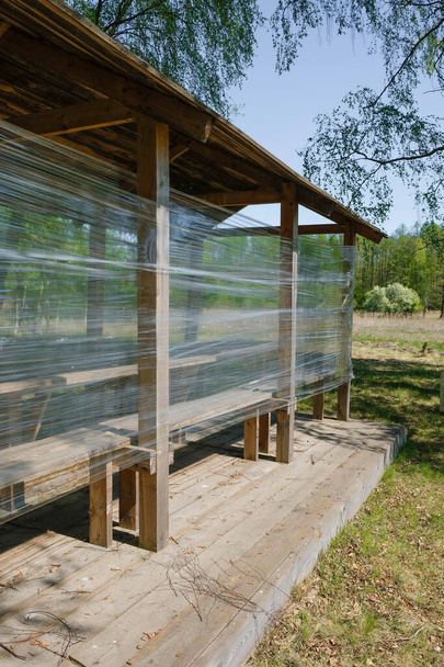 Gazebo en bois isolé avec du film plastique sur le fond de la forêt en Ukraine. Image verticale
. - Photo, image