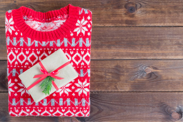Top view christmas sweater and gift on a wooden background. Flat lay and copy space. - Foto, immagini