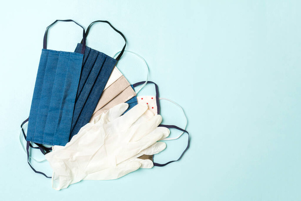Κάτοψη ενός σωρού από χειροποίητες βαμβακερές μάσκες και γάντια νιτριλίου σε μπλε φόντο. Έννοια προσωπικής προστασίας με χώρο αντιγραφής. - Φωτογραφία, εικόνα