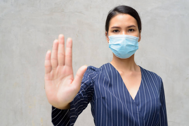 Ritratto di giovane imprenditrice asiatica con maschera per la protezione dall'epidemia di virus della corona contro il muro di cemento all'aperto - Foto, immagini