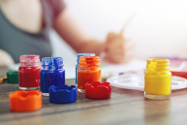 Blisko czerwone, niebieskie, żółte butelki farby akwarelowej ustawione na drewnianym miejscu pracy. Klasa sztuki lub koncepcja studia - Zdjęcie, obraz
