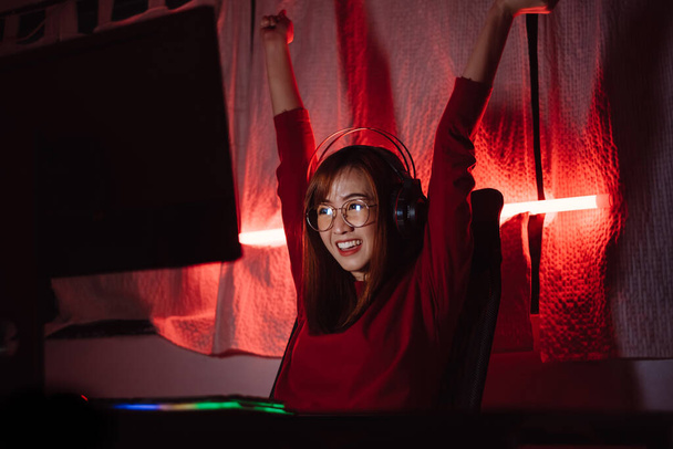 Pro player gamer winning the games young asian woman playing online shooting fps tournament ranking cyber internet at night red neon light room with gaming headset and keyboard on championship event. - Фото, изображение