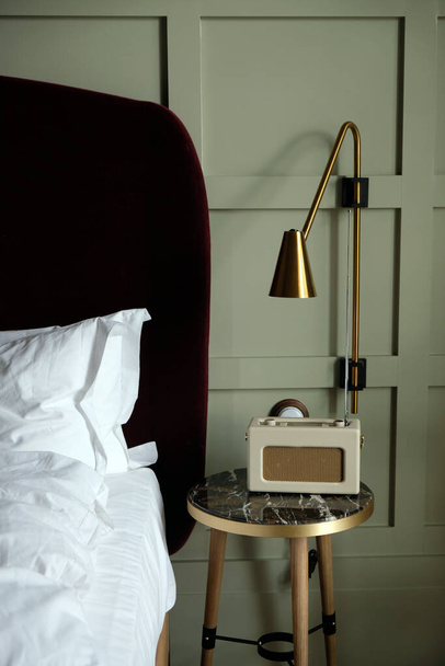 Cosy hotel bedroom minimalist interior with radio, golden lampshades and white bed sheets - Foto, imagen