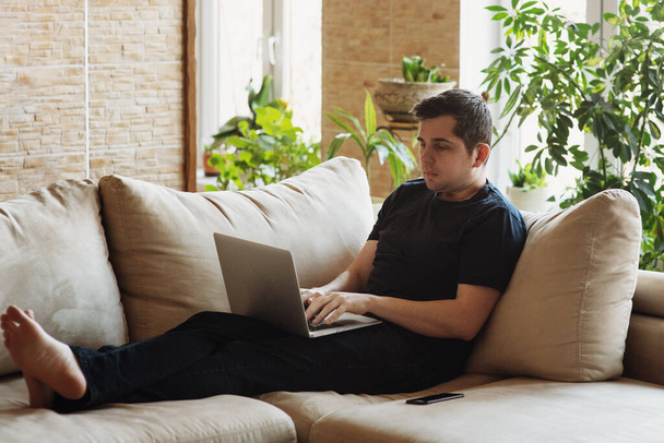 Man lying on sofa and working on his laptop. - Фото, зображення
