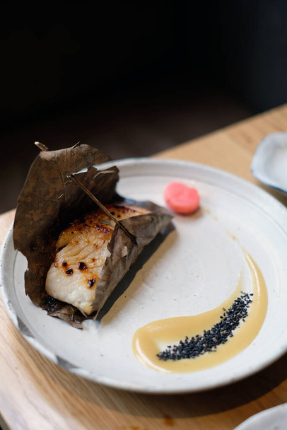Μια όμορφη μερίδα του κύριου πιάτο ψαριών που χαρακτηρίζει μπριζόλα ενός miso τζάμια κίτρινη ουρά με σάλτσα ταχίνι σε ένα ιαπωνικό εστιατόριο - Φωτογραφία, εικόνα