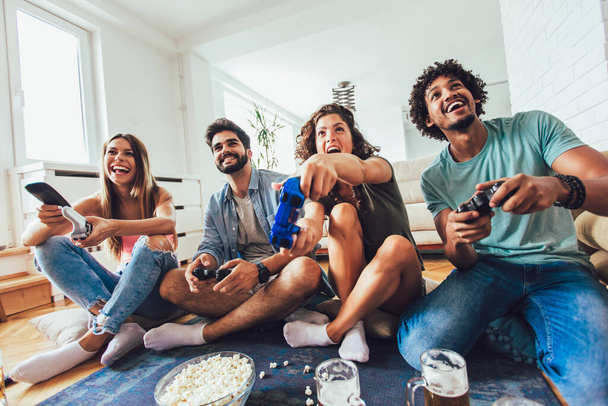 Grupo feliz de jovens amigos jogando videogames em casa
. - Foto, Imagem