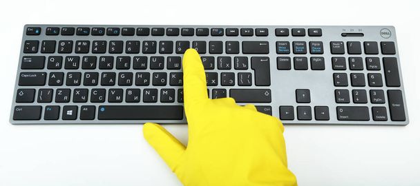 Warsaw, Poland - March 21, 2020:Dell Premier KM717 Black / Gray BT.Disinfection in public places, the fight against the virus, coronavirus. A working hand in a rubber glove points to a keyboard. - Zdjęcie, obraz