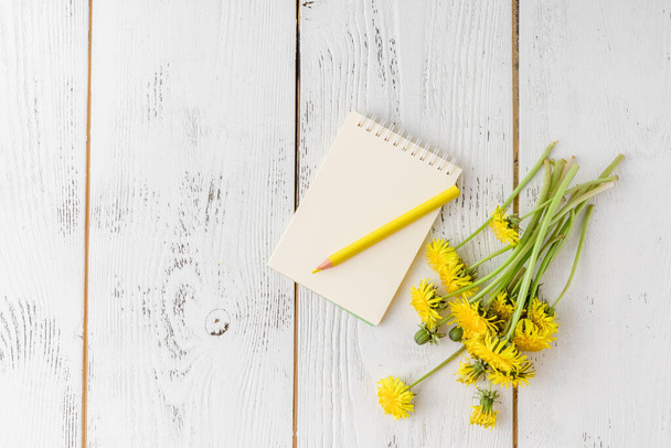 Bright dandelions, notebook com uma página em branco para as suas inscrições, colheres vintage em uma mesa bonita, branca, de madeira
.  - Foto, Imagem