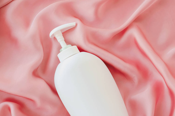 Etiqueta en blanco botella de envase cosmético como maqueta del producto sobre fondo de seda rosa
 - Foto, Imagen