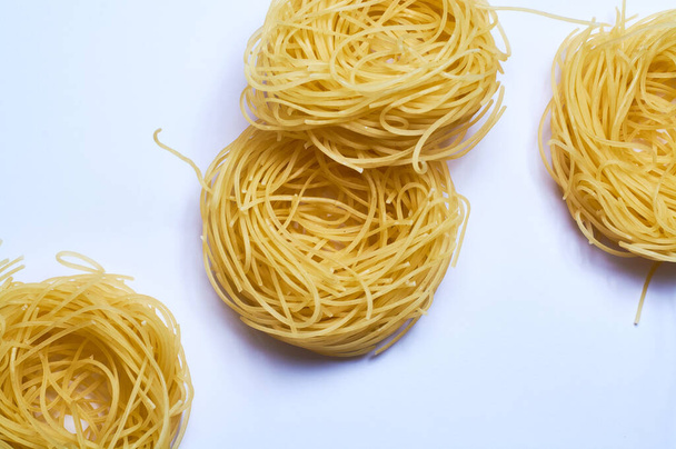 White background and thin Italian noodles, spaghetti, pasta of wheat, raw. - Photo, Image