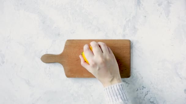 Woman cutting lemon on wooden board - Кадры, видео