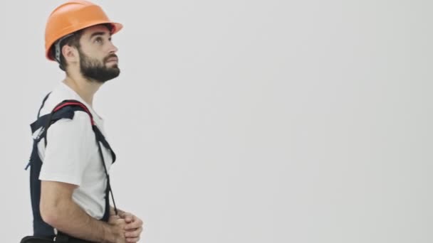 Concentrato giovane uomo costruttore idraulico a piedi con sacchetto isolato su sfondo muro bianco in casco
 - Filmati, video