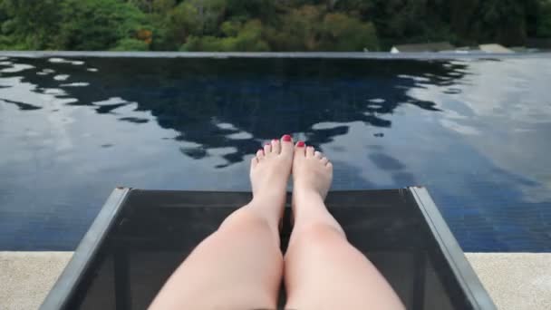 senhora de biquíni roxo preto fica na espreguiçadeira da piscina do hotel
 - Filmagem, Vídeo