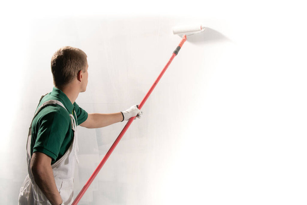 Decorador masculino pintando uma parede com cor branca - Foto, Imagem