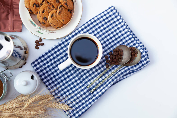 White cup of coffee and homemade round cookies with chocolate chips. Breakfast is on the table. Food at home. Still life. Coffee and coffee beans. An invigorating drink. - Zdjęcie, obraz