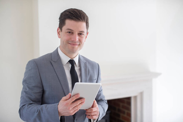 Retrato de agente inmobiliario masculino con tableta digital mirando alrededor y valorando nuevo hogar
 - Foto, Imagen