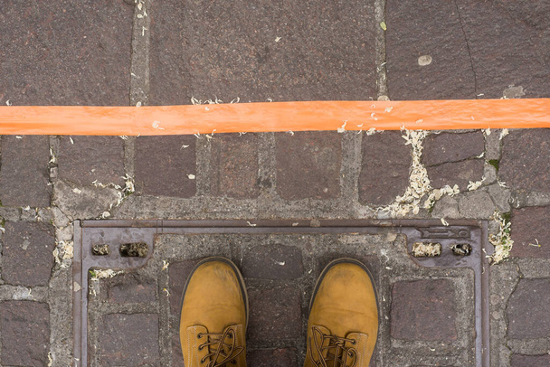 Fechar os pés em pé na estrada atrás da linha de cor laranja - Conceito de distância social
  - Foto, Imagem