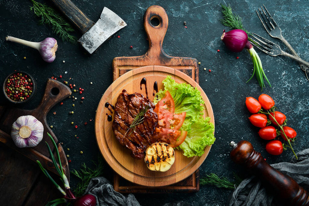 Juicy baked pork steak with vegetables on the board. Top view. - Foto, afbeelding