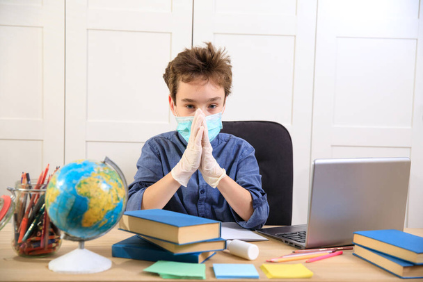 Uzaktan öğrenme çevrimiçi eğitim. Tıp maskeli çocuk evde çalışıyor, dizüstü bilgisayar başında çalışıyor ve okul ödevi yapıyor. Coronavirüs karantinası - Fotoğraf, Görsel