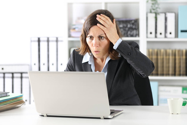 Surprise femme exécutive faisant erreur sur un ordinateur portable assis sur un bureau au bureau
 - Photo, image