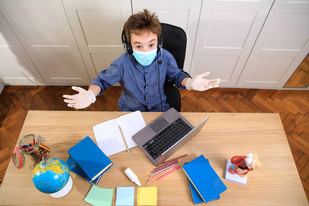 Distance learning online education. A schoolboy boy studies at home and does school homework. A home distance learning , Coronavirus pandemic in the world. Closing schools - Фото, зображення
