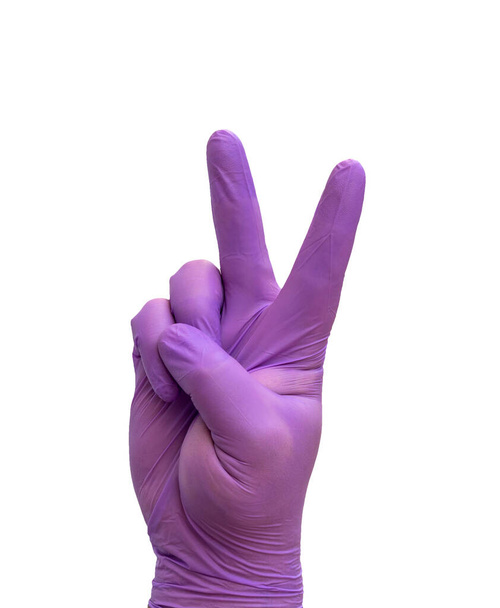 kéz orvosi kesztyű csinál a győzelem gesztus, szimbolizálja a győzelem COVID-19. - Fotó, kép