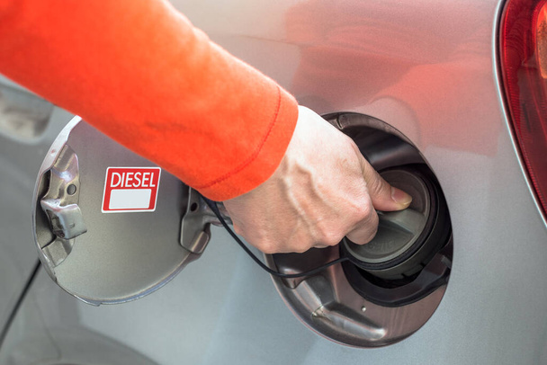 Woman opening the filler cap of a diesel car at a petrol station. Selective focus. - Photo, Image