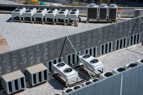 Equipo de unidades de aire acondicionado en un techo de grava de un edificio industrial. Ventiladores HVAC
. - Foto, imagen