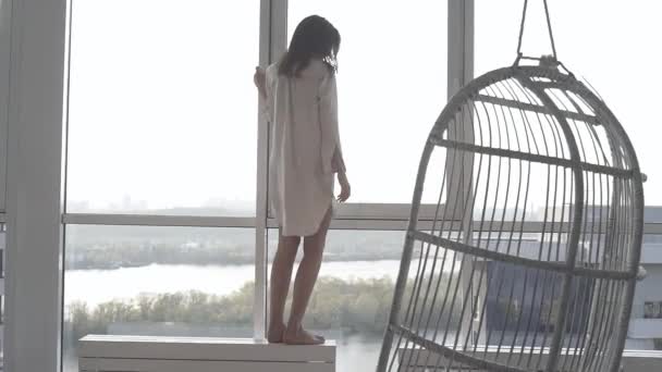A sexy model poses at sunset in her apartment with panoramic windows. emotion evening mood calm, outside the city and the Dnieper river. - Metraje, vídeo
