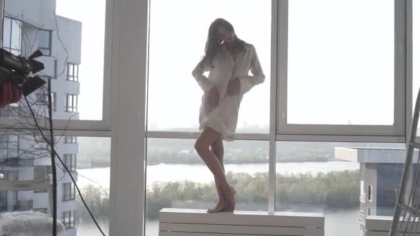 A sexy model poses at sunset in her apartment with panoramic windows. emotion evening mood calm, outside the city and the Dnieper river. - Záběry, video