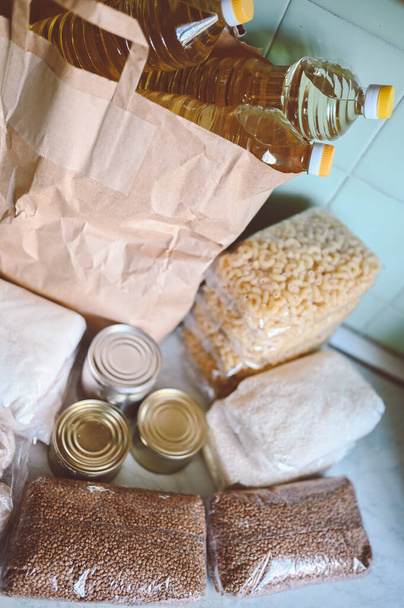 Volunteer donation various product set for poor or elderly people. Pandemic coronavirus food shortages. Food donations or delivery concept on kitchen background.  - Photo, Image