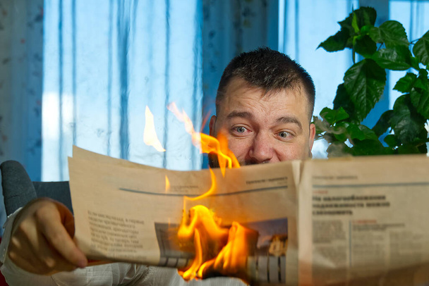 Geschäftsmann, der heiße Nachrichten liest oder Börsennachrichten Aktienkurse liest. Brennendes Magazin in den Händen der Menschen - heißes und aktuelles Konzept - Foto, Bild