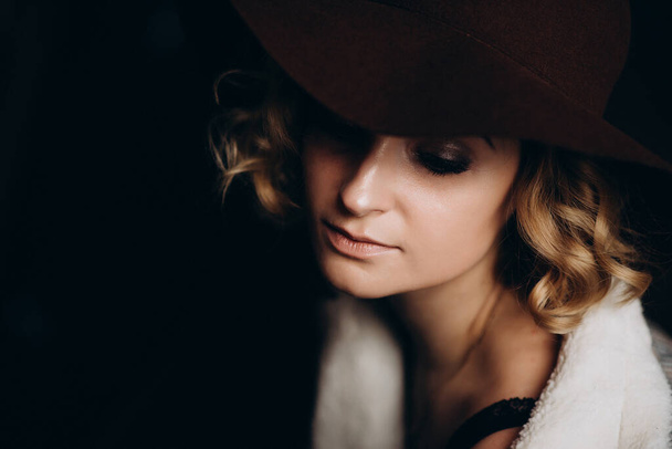 Beautiful elegant blonde girl in a hat on a dark background. Copy space for text. Soft focus. - Photo, Image