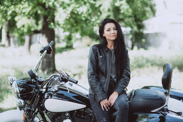 Menina motociclista sexy em uma jaqueta de couro está sentado em sua motocicleta. Foco suave
. - Foto, Imagem