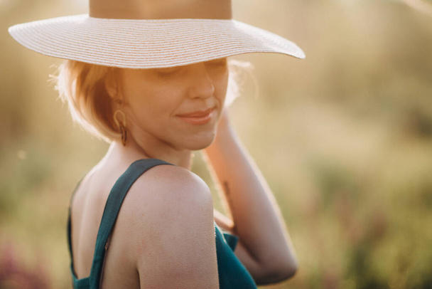 Nahaufnahme Porträt eines schönen blonden Mädchens mit Hut im Morgengrauen. Weiche selektive Fokussierung. - Foto, Bild