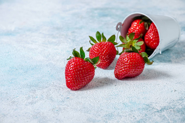 Fresas frescas en pequeño tablero de cubo blanco sobre fondo claro
. - Foto, Imagen