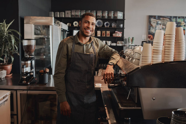 Başarılı afro-amerikan erkek işadamı bir kahve dükkanının arkasında kameraya bakarak gülümsüyor. - Fotoğraf, Görsel