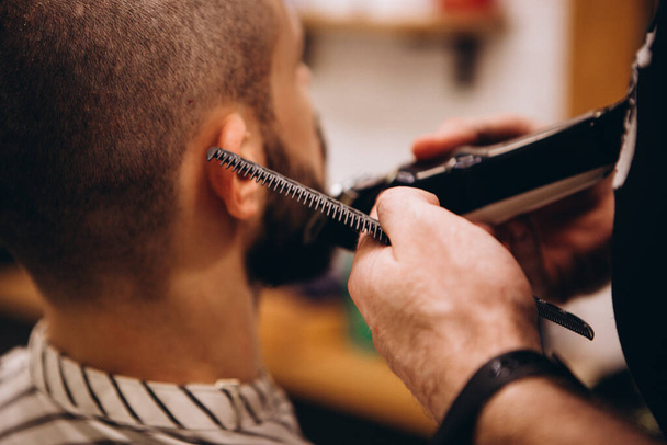Work in the Barber shop. Barber shaving a bearded man in a barber shop, close-up. Master cuts hair and beard  - Φωτογραφία, εικόνα