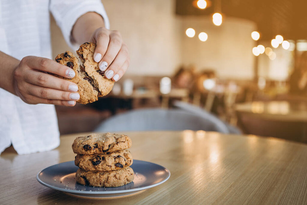 close up photo of delicious and crunchy oatmeal cookies on the backdrop of a cozy restaurant or bakery interior, festive Christmas mood, 4 cookies lying on top of each other - Fotó, kép