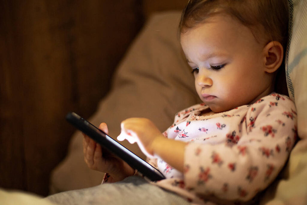 parental problems in parenting. A little kid has a gadget addiction, plays gadgets all the time, watches videos on a smartphone and falls asleep with only the phone in his hands - Valokuva, kuva