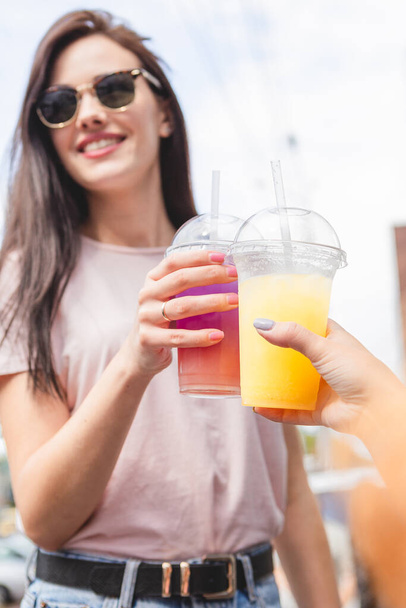 pretty and attractive woman holding a plastic glass with a cold multicolored summer cocktail with a good smile and cheerful mood - Fotó, kép