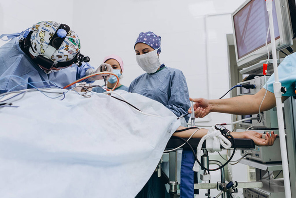 03.09.2019 Kyiv, Ukraine: Team of professional Surgeons Performing Invasive Surgery on a Patient in the Hospital Operating Room. Nurse Hands Out Instruments to surgeon, Anesthesiologist Monitors Vitals.  - Foto, Imagem