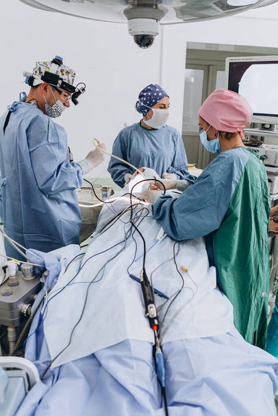 03.09.2019 Kyiv, Ukraine: Professional chief surgeon uses advanced tools, camcorders, lasers and endoscopy during surgery. team work of surgeons on real operation. Selective focus, noise effect - Foto, afbeelding