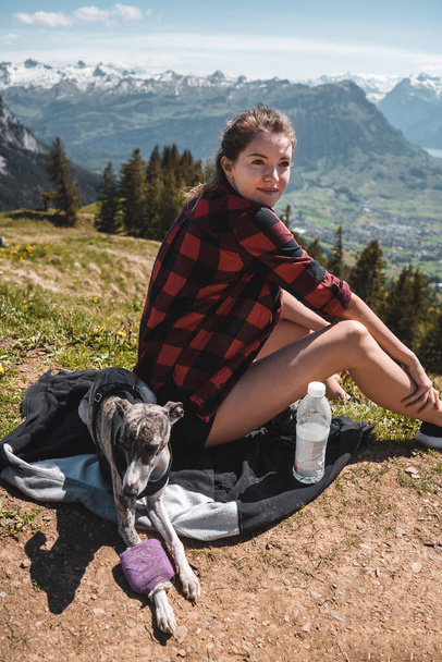 Жінка в плетеній сорочці з фрагментом на лузі дивиться на озеро і гори на задньому плані
. - Фото, зображення