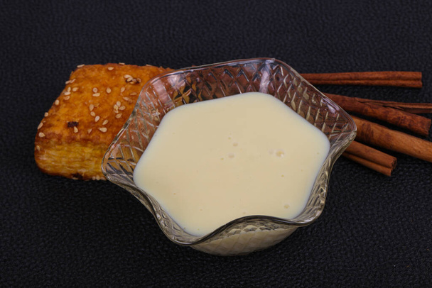 Mleko skondensowane w misce z paluszkami sinnamonowymi i ciastem - Zdjęcie, obraz