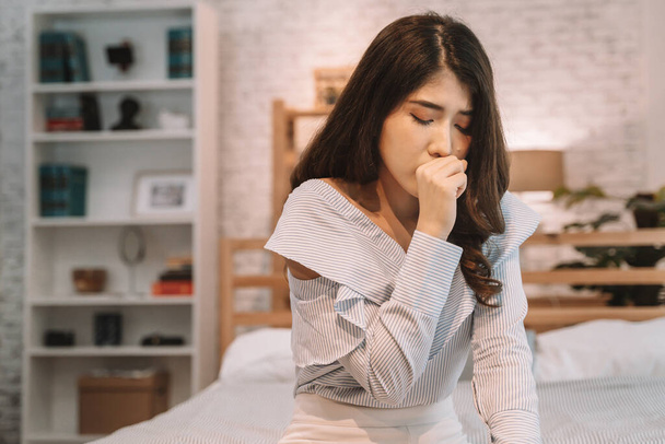 Portrait of 20s young Asian woman having dry cough in bedroom at home - Photo, image