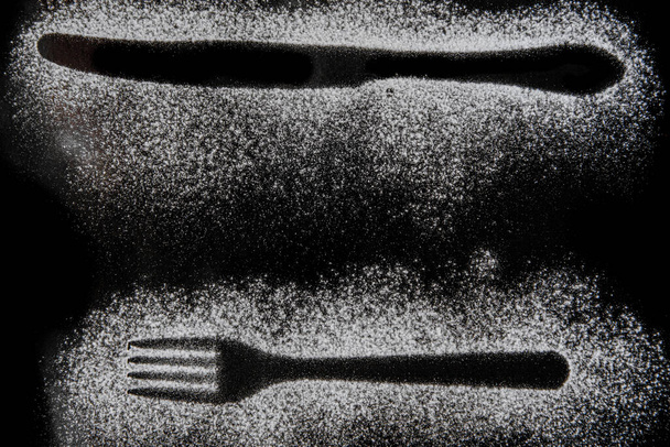 黒を基調に小麦粉で作ったフォークとナイフのシルエット - 写真・画像