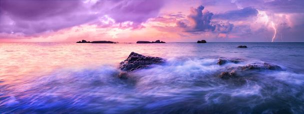 Mar tranquilo colorido durante la puesta del sol. Se acerca una tormenta sobre el horizonte. Nubes oscuras de colores en el aire, descargas eléctricas anuncian la tormenta que viene. - Foto, imagen