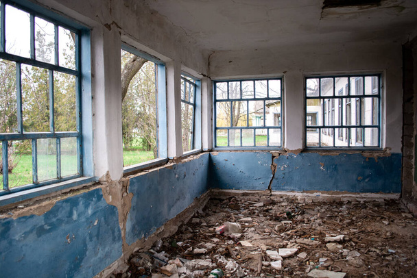 Bina savaştan zarar gördü. Kırık camlar, çatlak duvarlar, yerde bir sürü çöp. Eski evlerin yıkılması.. - Fotoğraf, Görsel
