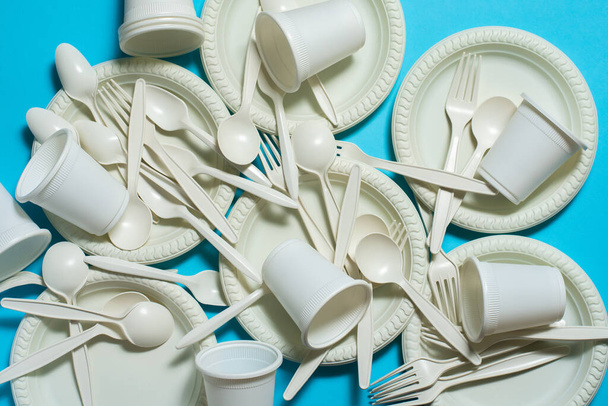 eco-friendly disposable tableware on a blue background. isolate. spoons, forks, plates, glasses of corn starch. biodegradable dishes. natural materials for replacing plastic. - Photo, Image